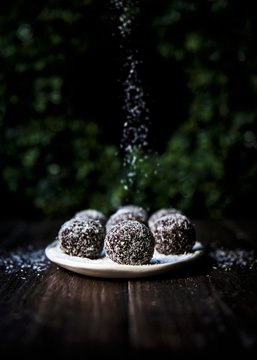 A plate of spiced chocolate brownie rum balls rolled in coconut flakes
