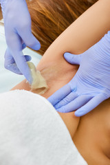 The doctor on sugaring in a beauty salon removes hair from axills of the girl
