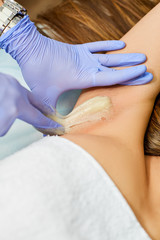 Naklejka premium The master of sugaring puts paste on the girl's armpits
