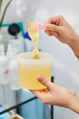 The sugaring master stirs the paste in the jar before the epilation procedure