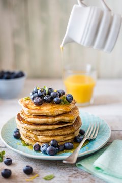 Sstack of pancakes with lemon zest, bueberries and maple syrup for breakfast