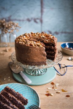 Chocolate almond cake with brittle topping on a cake stand with a slice removed