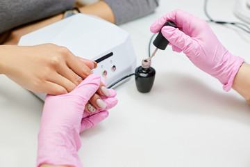 The master does the girl's manicure. Application of nail polish.