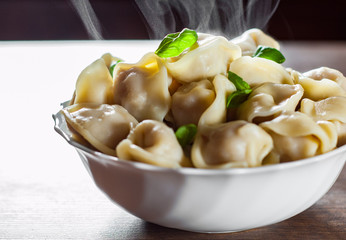 Meat dumplings - russian pelmeni, ravioli with meat in bowl on a wooden table background