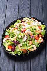 Mix of salad with shrimps , avocado and cherry tomatoes . Healthy food background