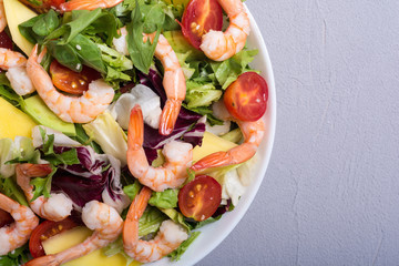 Mix of salad with shrimps , avocado and cherry tomatoes . Healthy food background