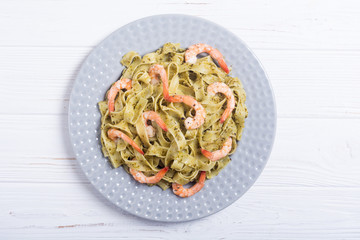 Pasta tagliatelle with sauce pesto and shrimps . Italian food background
