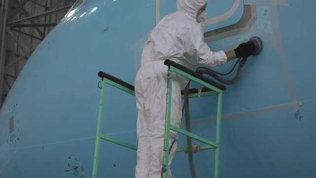 Painting the aircraft at the factory. The engineer repairing the aircraft. Maintenance of passenger aircraft. Repair of an aircraft wing. Passenger plane in the hangar in the repair. 4K
