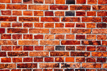 Detail of old and weathered grungy red brick wall marked by the long exposure to the elements as surface texture background.
