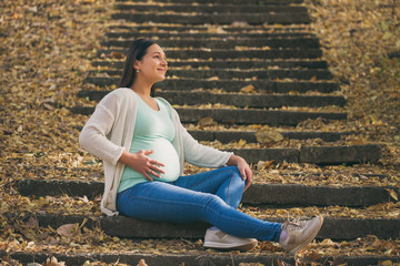 Fototapeta na wymiar Happy pregnant woman relaxing in park. 