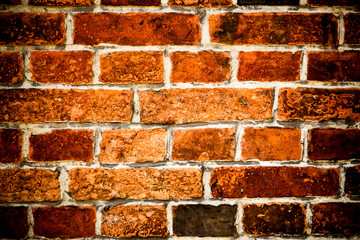 Detail of old and weathered grungy brown and red brick wall marked by the long exposure to the elements as surface texture background with vignetting.