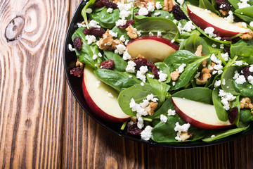 Autumn spinach salad with apple , cheese , walnut and dried cranberry . Healthy vegetarian food