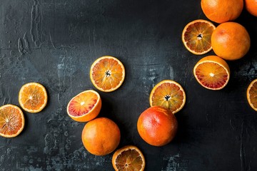Blood oranges: whole, halved and sliced on a black background