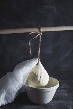 Close up of ricotta in cheesecloth draining into bowl