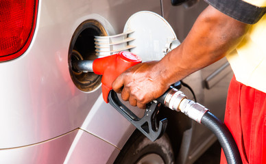 Hand of worker man refuelling a car at the petrol station. Concept photo for use of fossil fuels...
