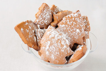 Holiday gingerbread like a new year trees with sugar icing in glass bowl on a neutral nackground