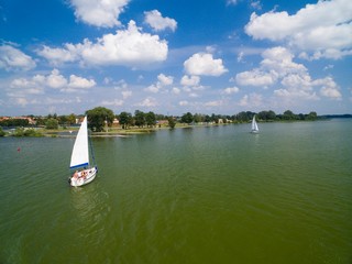 Aerial view of yacht sailing on Niegocin Lake, Gizycko town in the background, Mazury, Poland