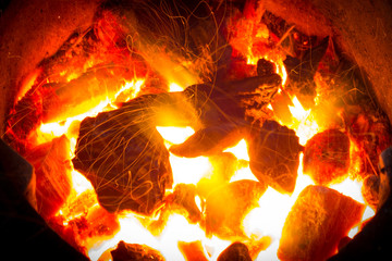 Fototapeta premium burning charcoal background with fire and sparks.Coals burning flameless in fireplace.flames of fire with sparks background.Live Coals .Beautiful in soft and blur style for background.