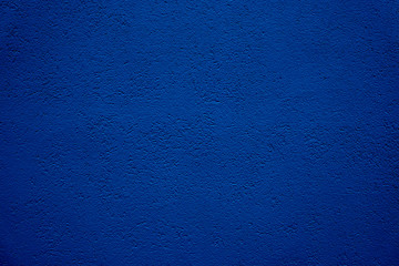 Dark blue wall background. Grain stucco plaster wall from a house coarse exterior facade as an...