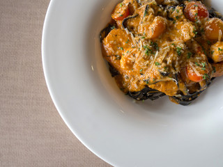 Black Spaghetti in tomato sauce with shrimp, tomato sprinkle with spices and cheese on white plate.Fresh and clean dishes look delicious and yummy
