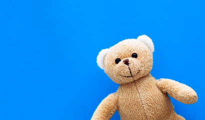 Brown teddy bear child toy isolated in a seamless pastel blue coulor with large empty space background.