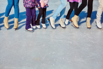 Close-up of the skates from the skaters on the ice surface. Skate on the ice in the company of friends. Skate rental.  place for text