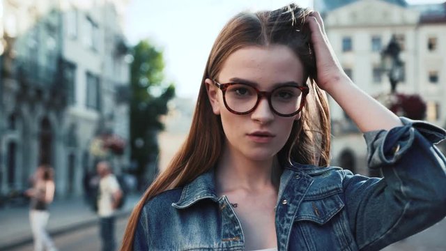 Beautiful young woman walking down the city street turns to camera and gives a lovely playful smile feel happy girl lady jacket lifestyle face summer close up slow motion