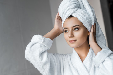 smiling young woman in white bathrobe wearing towel on head