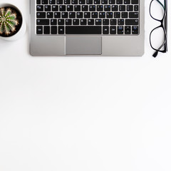 Real top view photo of white desk copy space with laptop, glasses and cactus