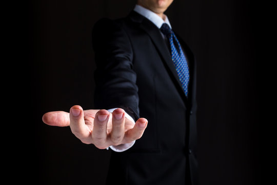 Man in a business suit holding his hand out and showing something