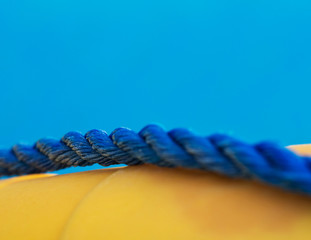 Close-up of blue marine twisted rope on yellow lifebuoy, shallow dept of field