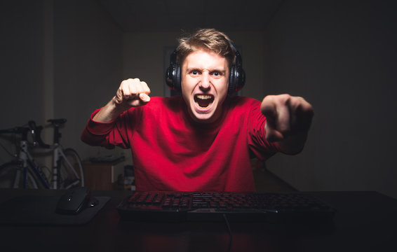 Gamer is going to make revenge that's why he is holding his fists in attack position Young man playing game at home and streaming playthrough or walkthrough video.