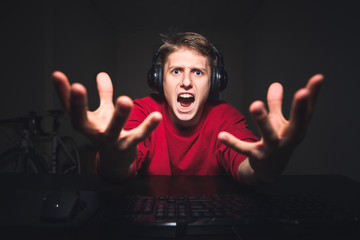 Gamer lost in the online video game, so angry. Portrait of an evil gamer playing games at night on...