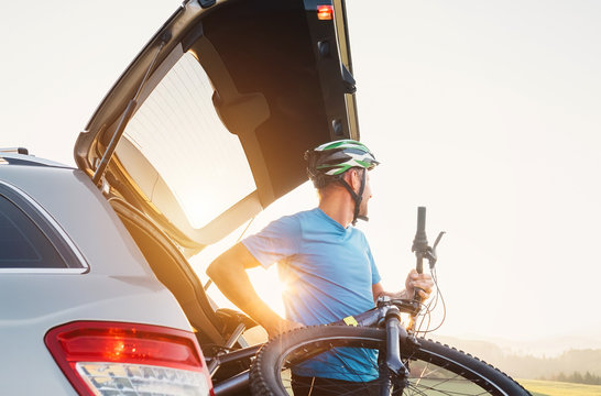 Man taking his bicycle out from the trunk of a car. Sport leisure concept image