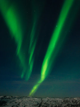 Beautiful stripes of the northern lights, aurora in the night sky above the hills.