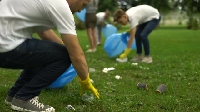 Active citizens collecting garbage in public park, society against pollution