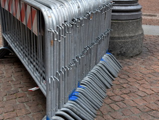 Auf Kopfsteinpflaster stehende Absperrgitter in einer Reihe 