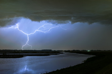 Naklejka na ściany i meble A bizarre lightningbolt strikes down to earth near a lake in the vicinity of Rotterdam, The Netherlands