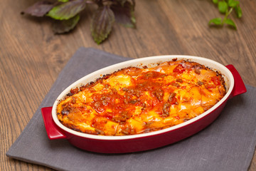 Italian food. Hot tasty freshly baked lasagna served with basil herb on wooden table.