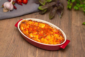 Italian food. Hot tasty freshly baked lasagna served with basil herb on wooden table.