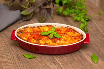 Italian food. Hot tasty freshly baked lasagna served with basil herb on wooden table.