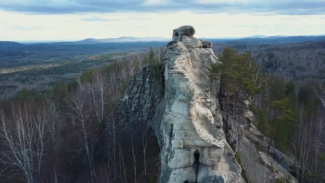Aerial; extremely near drone flight along the stone wall over the tree crones; late autumn landscape with bare trees, mixed forest and lakes on background; season change; ecology, clear air concept