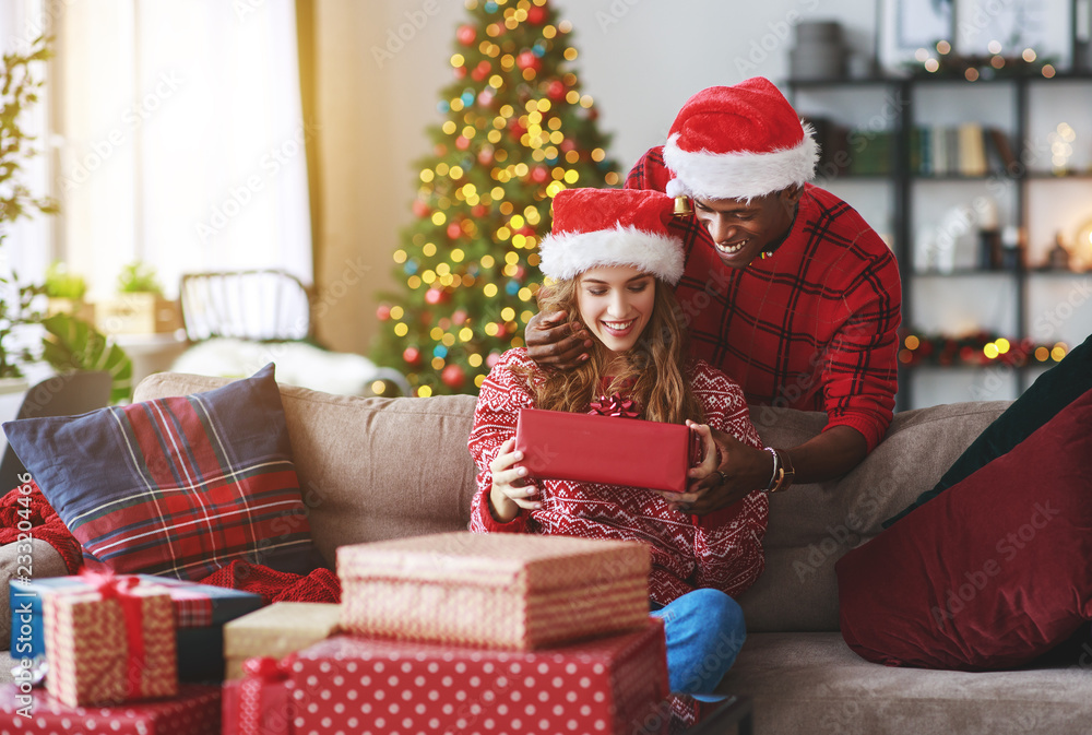 Wall mural happy couple opening presents on christmas morning