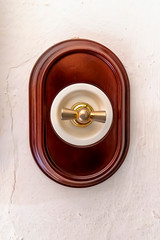 old and luxury rotary electrical switch mounted in a lime wall