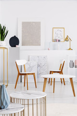 Real photo of white daily room interior with chairs, tables and painting