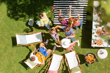 Top view on friends dancing next to sunbeds and table during grill party in the garden