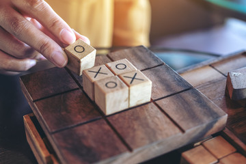 Closeup image of people playing wooden Tic Tac Toe game or OX game