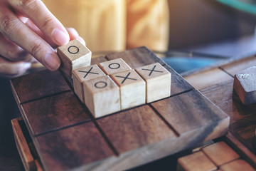 Closeup image of people playing wooden Tic Tac Toe game or OX game