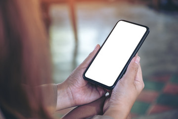 Mockup image of a woman holding black mobile phone with blank desktop screen in cafe
