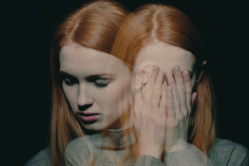 Porter of beautiful redhead girl with psychotic disorders covering her face, hiding from her...